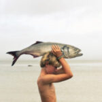 Photo of man holding fish above head
