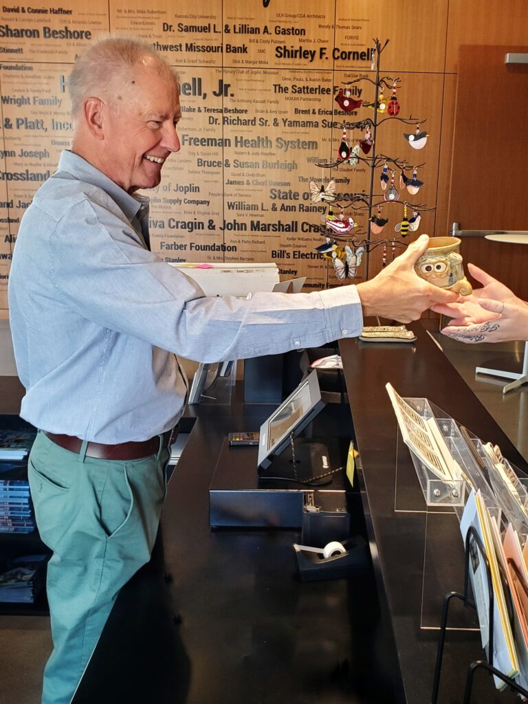 Volunteer helping guest in gift gallery.